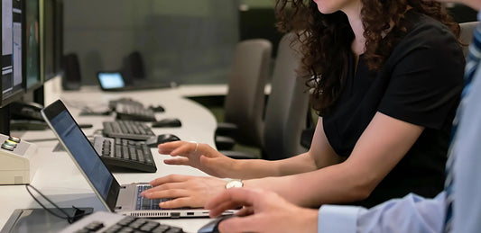 Deux personnes travaillent côte à côte sur des postes informatiques