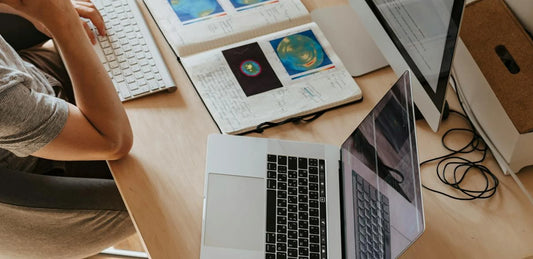 Un bureau vu de haut avec un ordinateur portable, un carnet et un écran