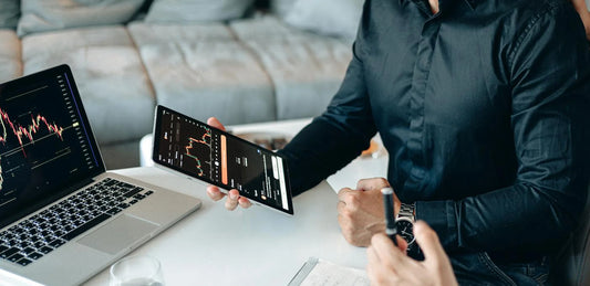 Une personne consulte des graphiques sur une tablette à côté d’un ordinateur portable